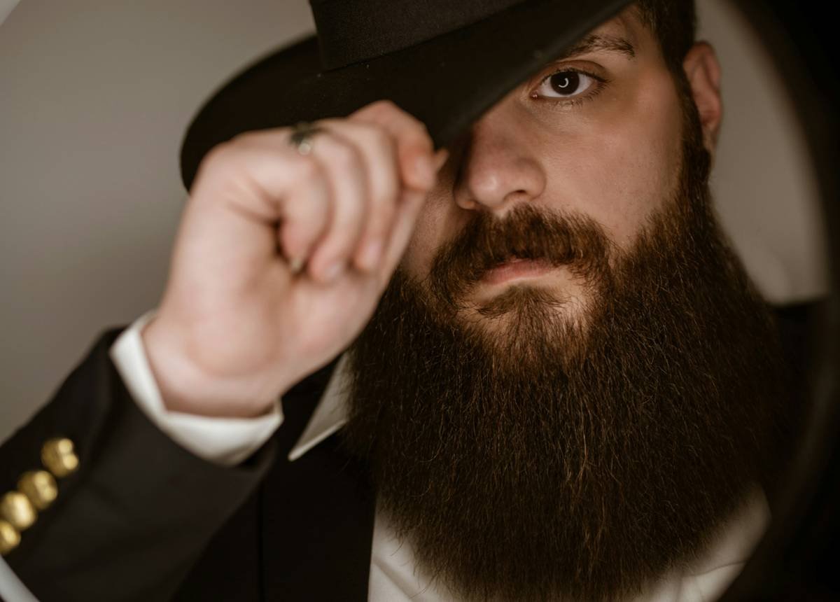 Professional using beard grooming and styling tools on a client with coarse beard texture